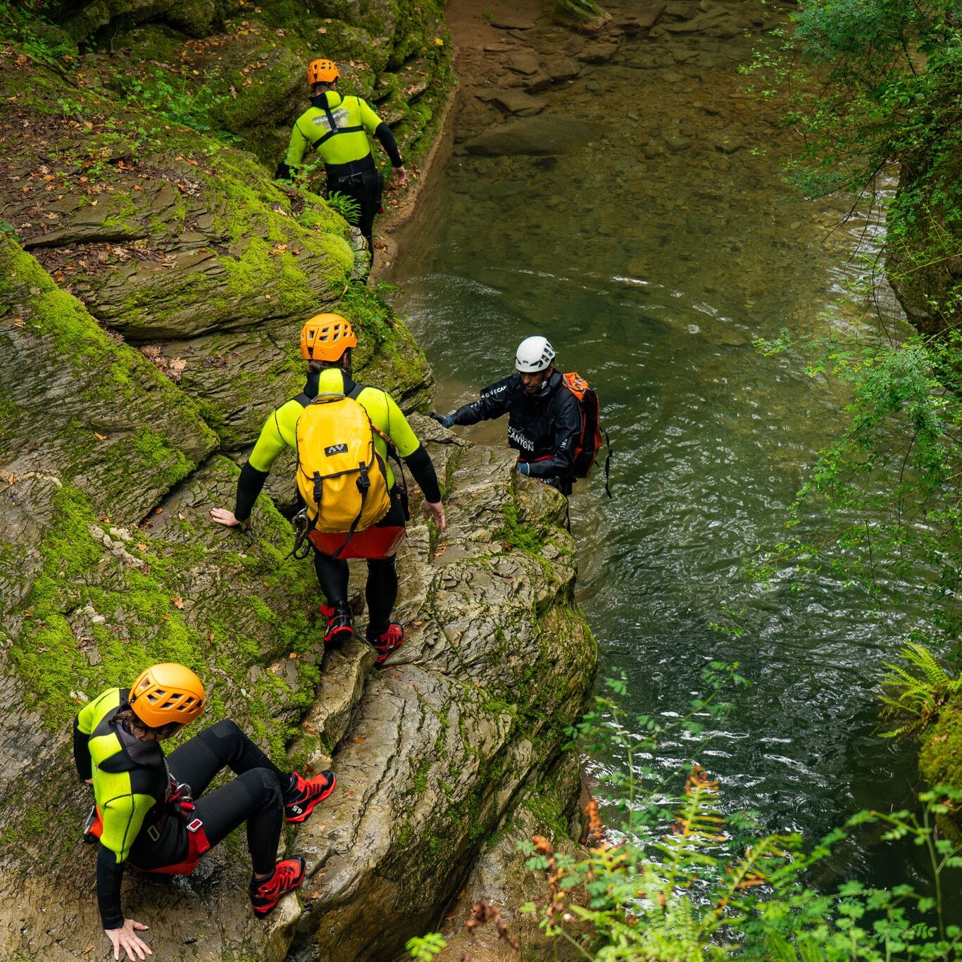 Partecipanti durante un tratto tecnico di canyoning al Rio Buti, Vaiano (Prato), mentre percorrono una cengia rocciosa sopra il torrente. La guida assiste il gruppo lungo le pareti naturali scavate dall’acqua, in uno dei percorsi più suggestivi per canyoning in Toscana vicino Prato. Ambiente naturale con rocce stratificate, acqua limpida e vegetazione fitta.